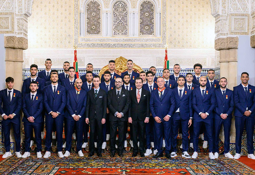 In this photo released by the Moroccan Royal Palace, Morocco's King Mohammed VI, centre, flanked at left by Morocco's Crown Prince Moulay El Hassan and Prince Moulay Rachid at right, poses with members of the Moroccan national football team in the throne room of the royal palace in Rabat, Morocco, Tuesday, Dec. 20, 2022. Morocco national team won the fourth place at the FIFA World Cup Qatar 2022. (Moroccan Royal Palace via AP)